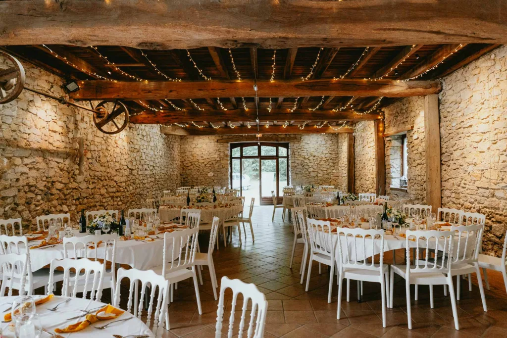Une réception de mariage dans une grange de meysonnave avec tables et chaises blanches.