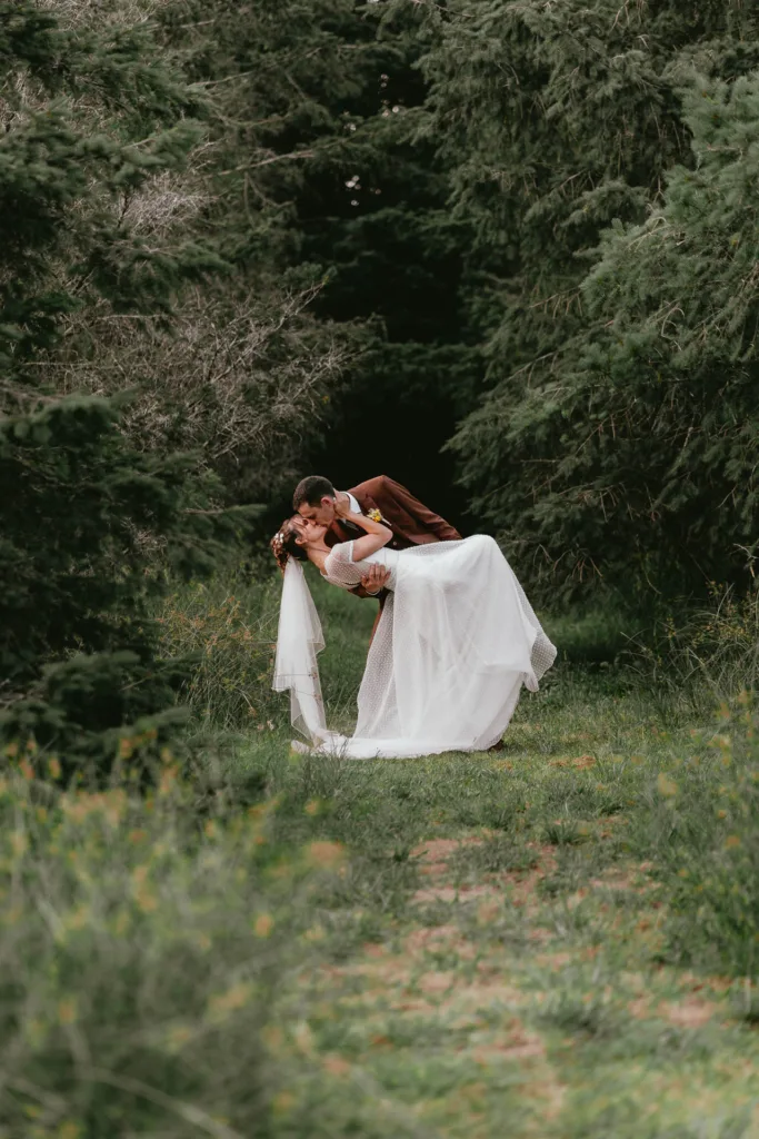 Des mariés s'embrassant dans les bois à la grange de mariage de Meysonnave.