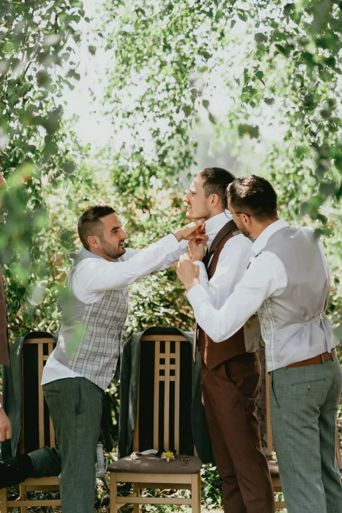 Un groupe de garçons d'honneur ajustant leurs cravates à la grange du mariage de Meysonnave.