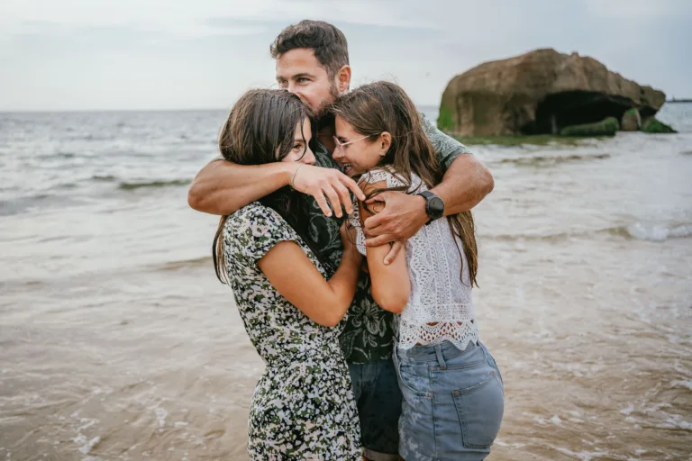 Un groupe familial s’embrassant sur la plage au bord de l’océan.