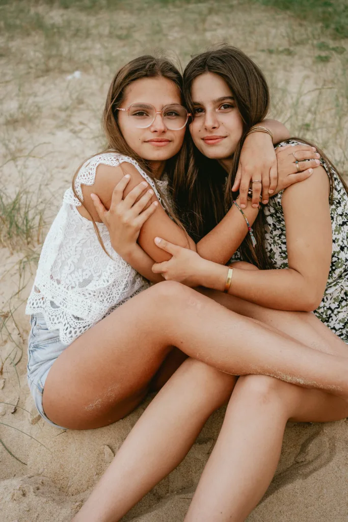 Deux filles s'embrassant dans le sable au bord de l'océan.