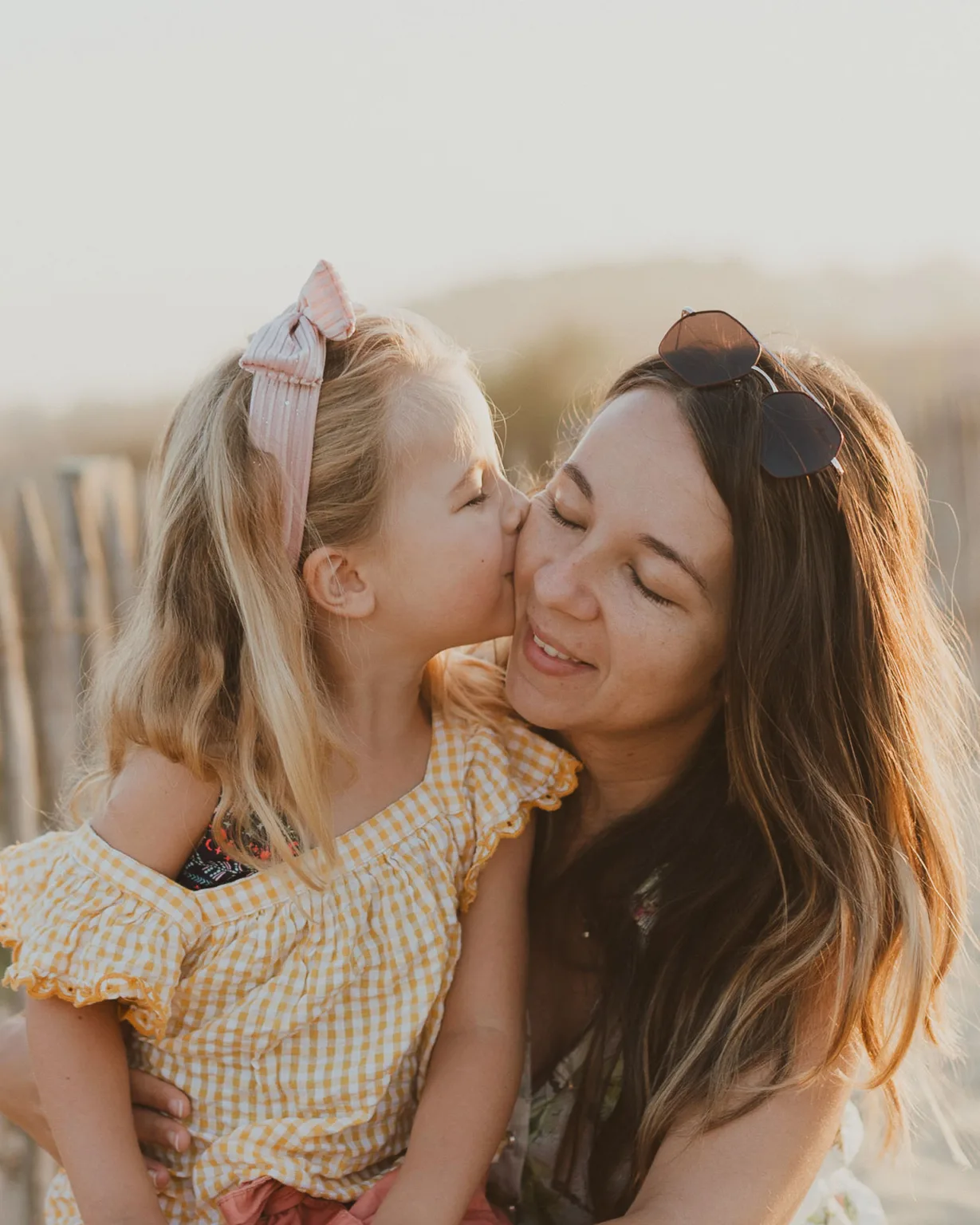 une mere photographe et sa fille lui faisant un bisous sur la plage landaise.