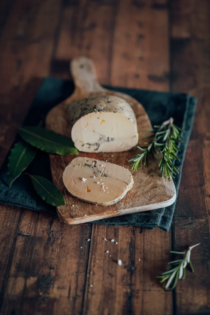 Le photographe culinaire landes capture du fromage sur une planche à découper en bois avec des brins de romarin.