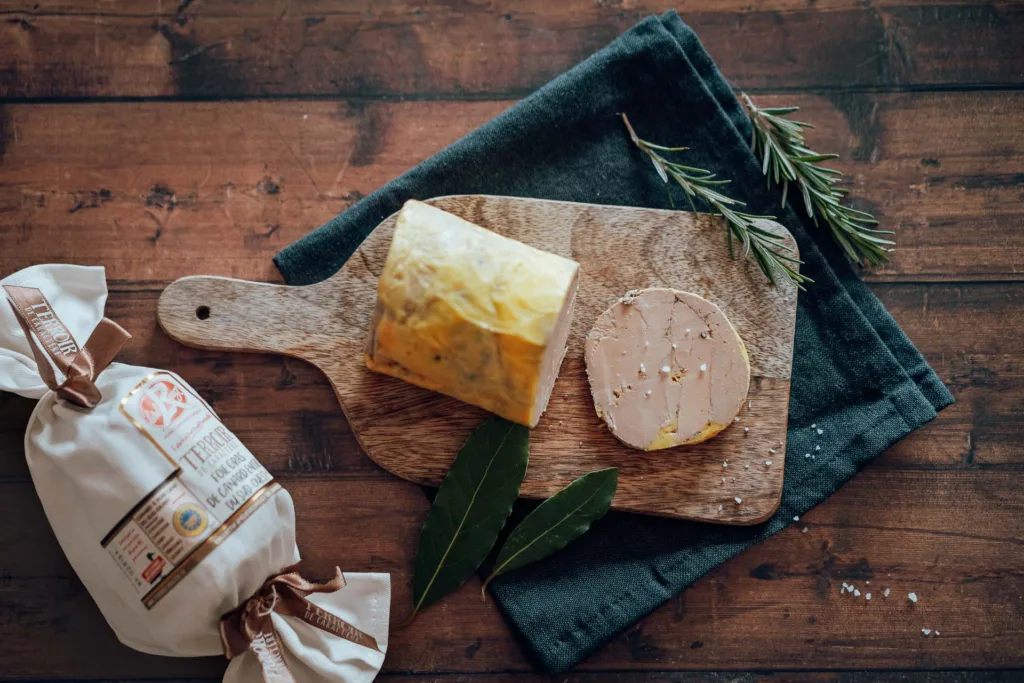 Une planche à découper en bois avec du fromage et des herbes dessus, photographiée par un photographe culinaire des Landes.