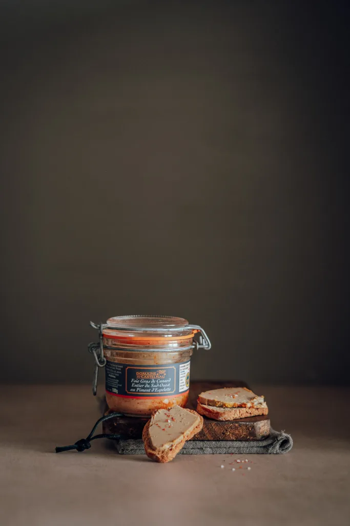 Un photographe culinaire des Landes capture un pot de moutarde et un morceau de pain sur une table.