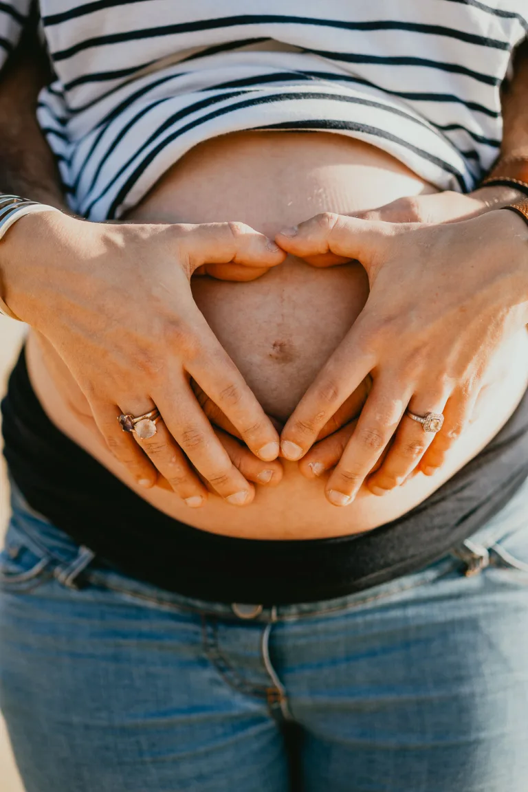 Une femme enceinte tient son ventre avec ses mains.