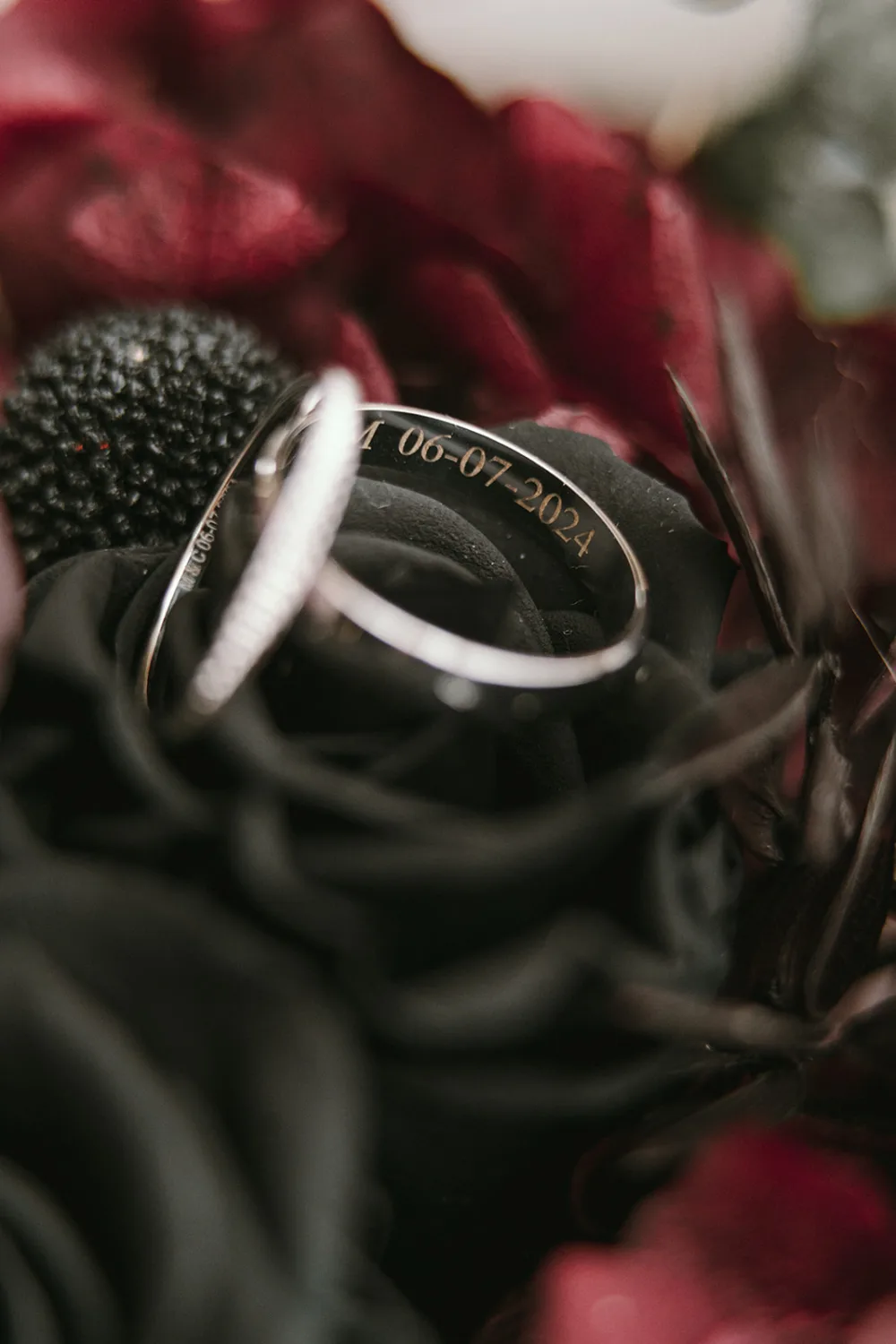 Cette image saisissante, capturée par un célèbre photographe famille Landes, présente en gros plan deux alliances en argent avec une date gravée (06-07-2024), posées délicatement sur des fleurs noires et rouges, symbolisant l'union et la passion lors d' 'un mariage mémorable dans les magnifiques Landes.