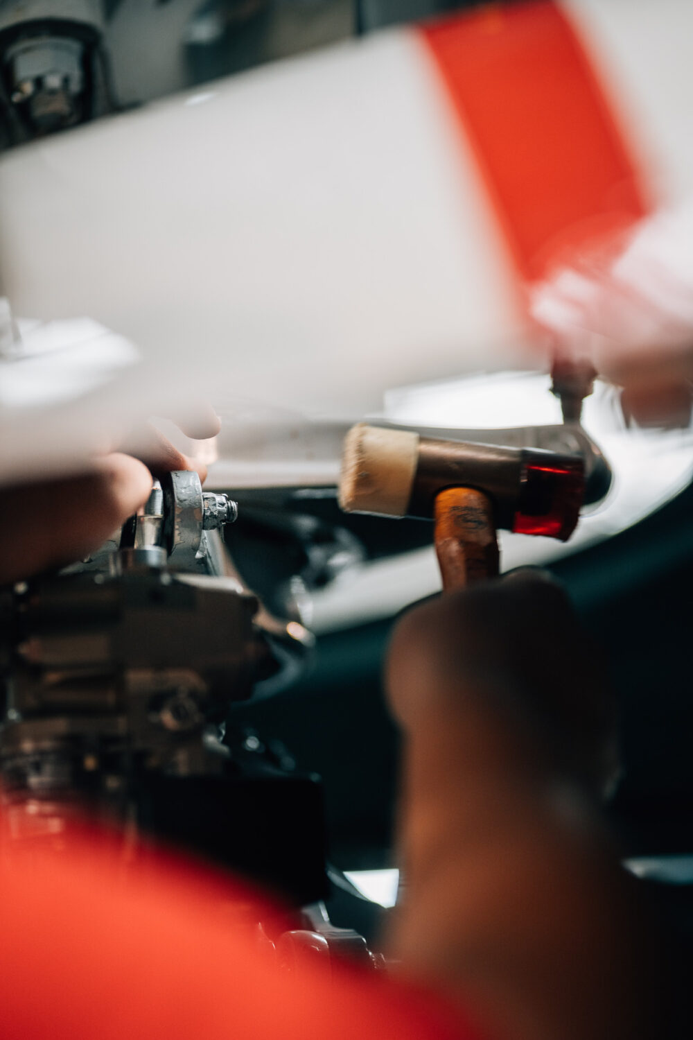 Pendant ses vacances dans les Landes, un photographe de mariage et de famille capte l'instant où une personne utilise un marteau pour ajuster délicatement les pièces d'un objet mécanique, illustrant la précision et le soin dans la capture des détails authentiques qui font la beauté d'un reportage photographique axé sur l'artisanat et les moments familiaux.