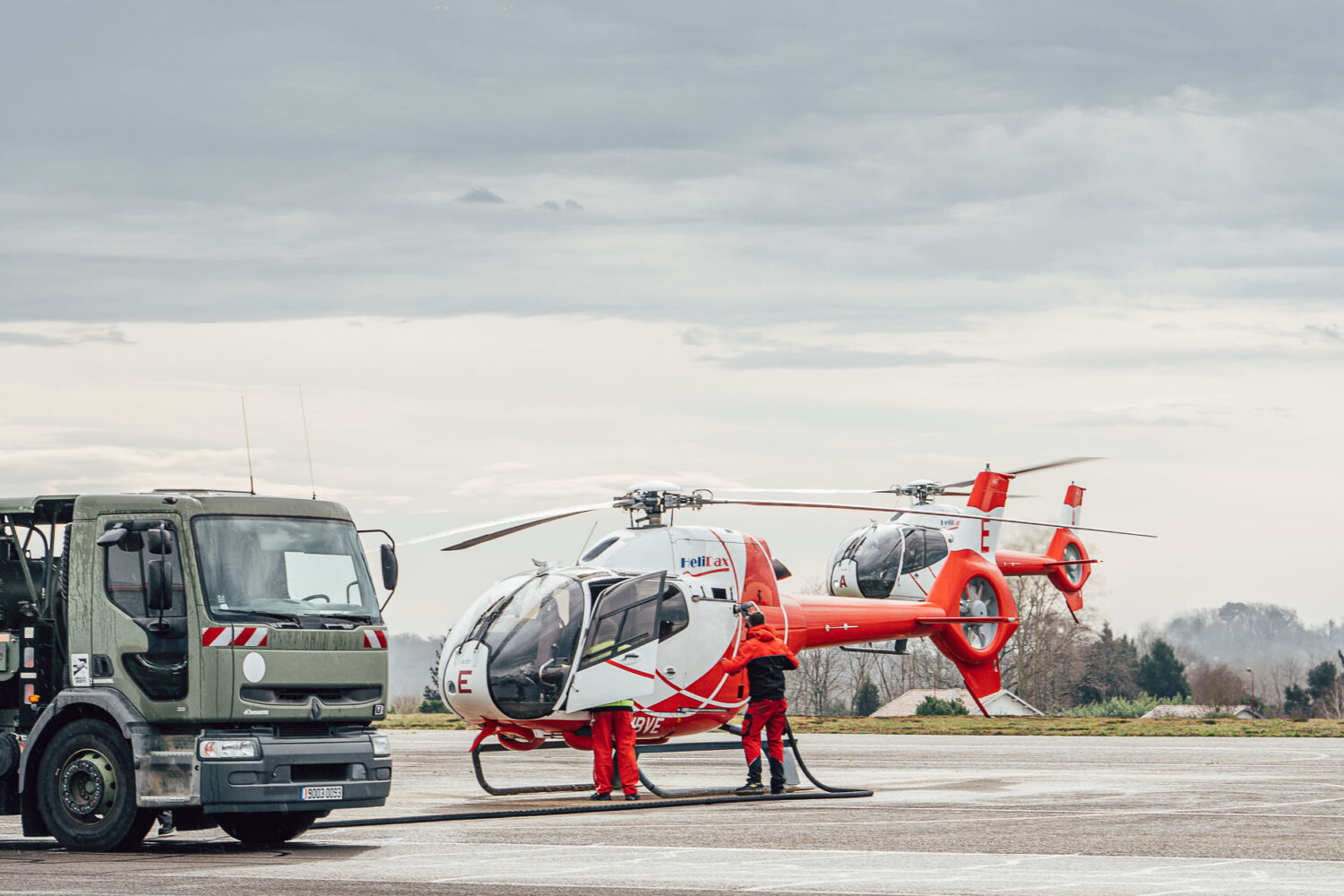 Cette scène captivante, où deux hélicoptères rouges et blancs sont stationnés sur le tarmac près d'un grand camion sous un ciel nuageux, évoque des souvenirs de vacances inoubliables dans les Landes, tandis que le personnel se tient prêt à l'aventure, reflétant l'aventure. 'essence même des occasions spéciales capturées par un photographe de mariage ou de famille passionnée dans cette région pittoresque.