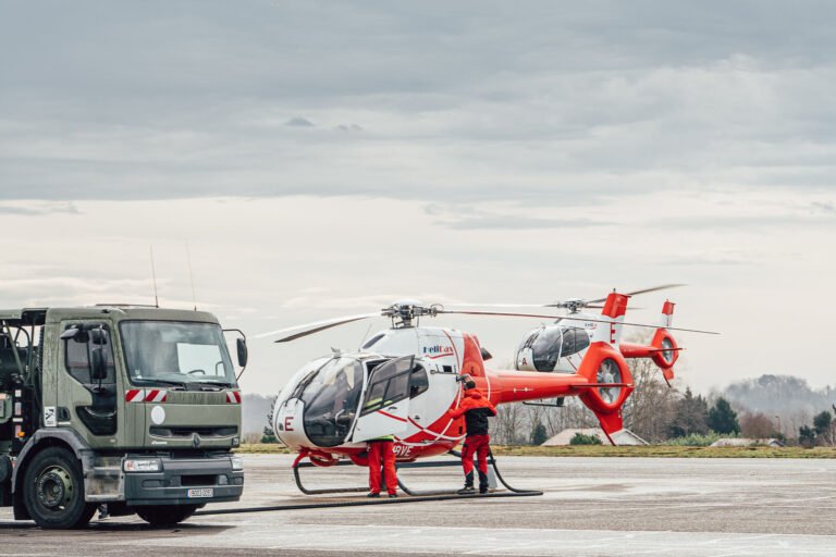 Cette scène captivante, où deux hélicoptères rouges et blancs sont stationnés sur le tarmac près d'un grand camion sous un ciel nuageux, évoque des souvenirs de vacances inoubliables dans les Landes, tandis que le personnel se tient prêt à l'aventure, reflétant l'aventure. 'essence même des occasions spéciales capturées par un photographe de mariage ou de famille passionnée dans cette région pittoresque.