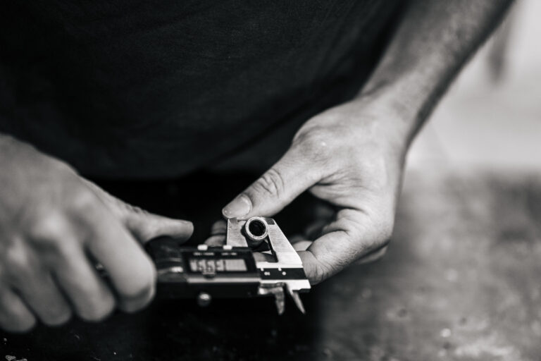 Cette image captivante capture un gros plan sur des mains expertes utilisant un pied à coulisse pour mesurer avec précision le diamètre d'un petit tube métallique, évoquant les outils minutieux d'un artisanat délicat que l'on pourrait apprécier lors de paisibles vacances dans les Landes, parfait pour illustrer l'attention aux détails et le savoir-faire exceptionnel recherché par les photographes de mariage et de famille désireux d'immortaliser des moments précieux et authentiques dans cette magnifique région.