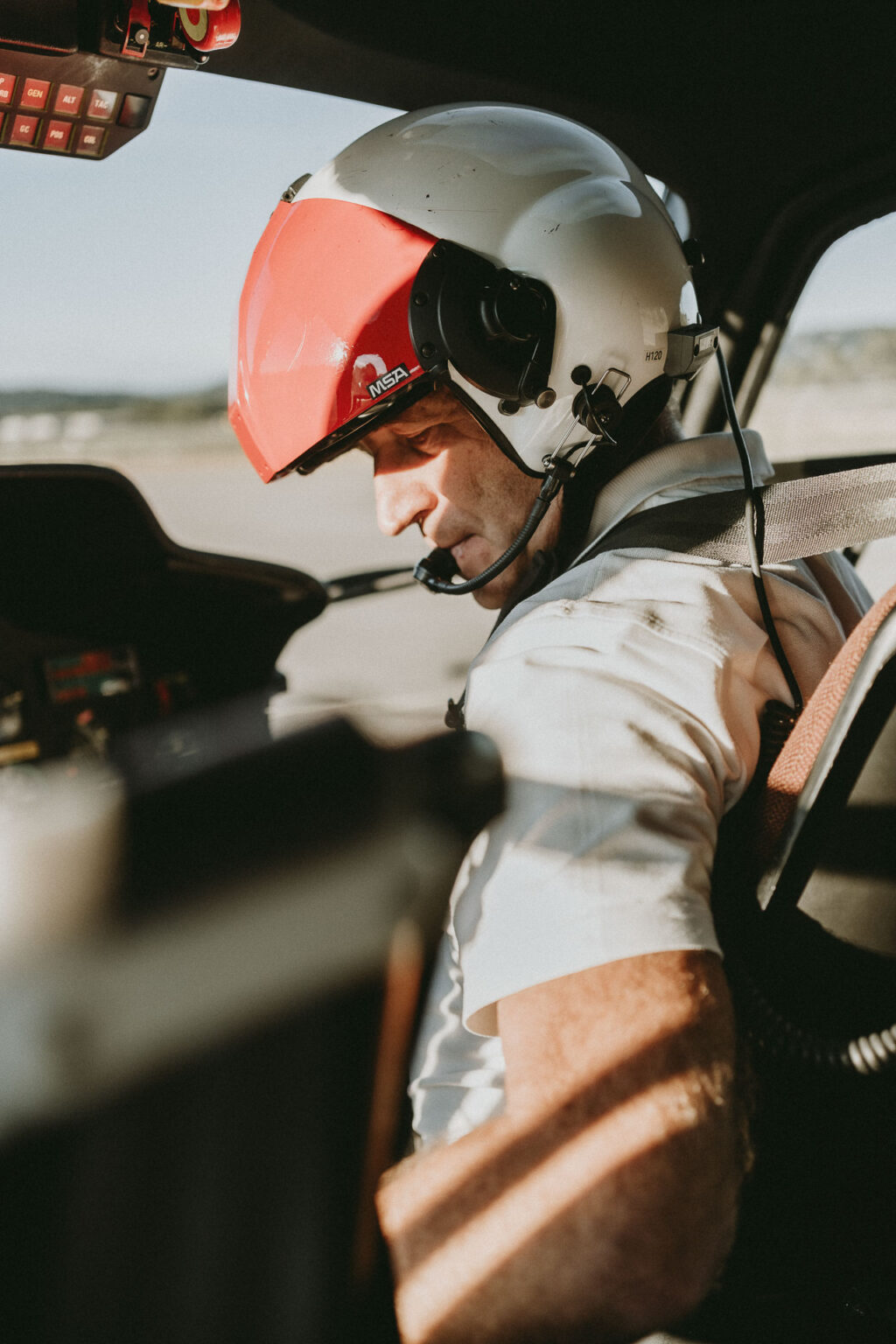 Dans cette saisie d'image par un photographe professionnel landais spécialisé dans les photos de mariage et de famille, un pilote est captivé par son environnement dans le cockpit d'un avion, portant un casque et un micro-casque tandis qu'il observe attentivement les commandes éclairées délicatement par la lumière du soleil traversant la fenêtre, illustrant une scène à la fois technique et empreinte de sérénité que ce talentueux photographe landais sait intégrer dans ses séries photographiques éblouissantes.