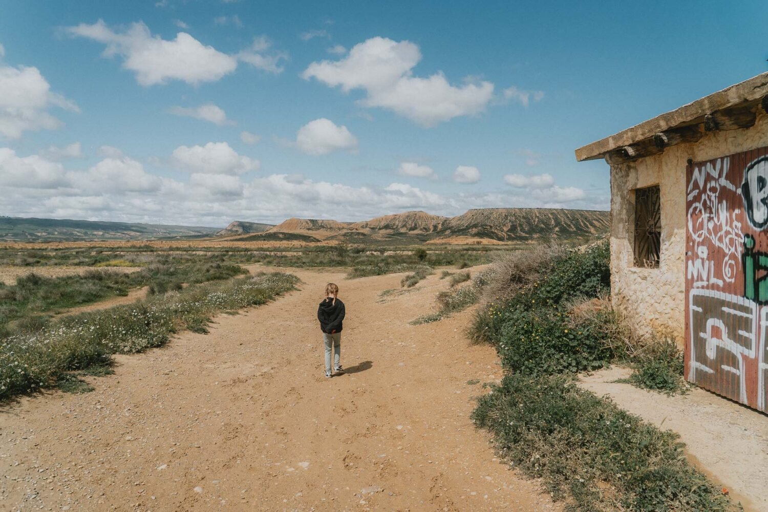 Une balade sur un chemin champêtre, face aux collines et à la bâtisse colorée, souvenir authentique d'escapade en famille.