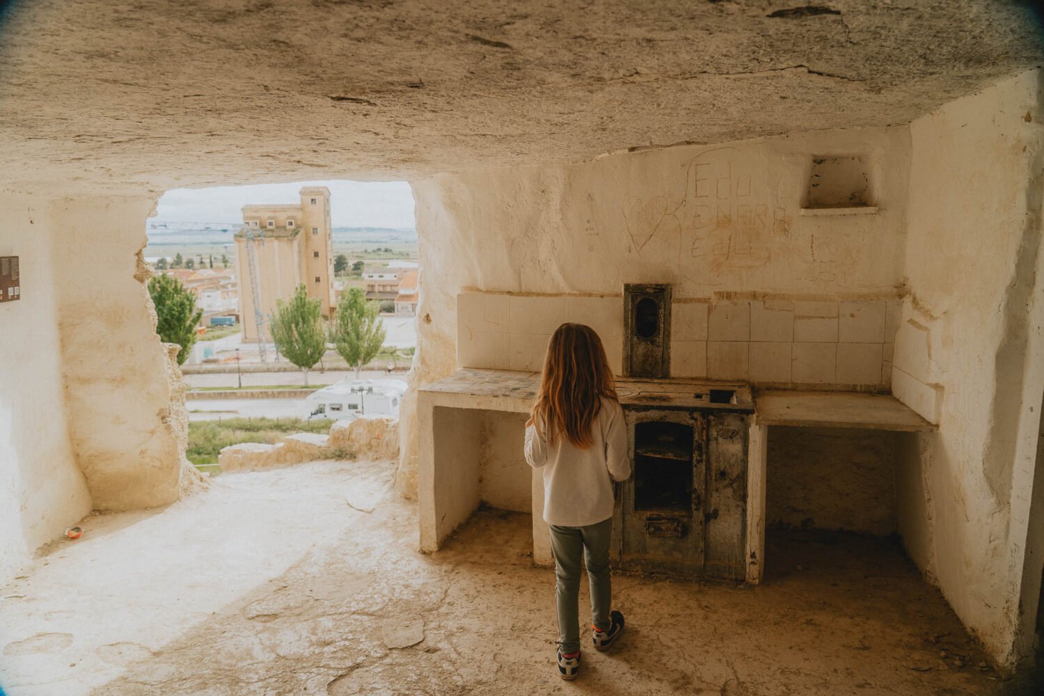 Une jeune fille contemple le paysage depuis une maison troglodytique authentique, instant de douceur capturée en famille.