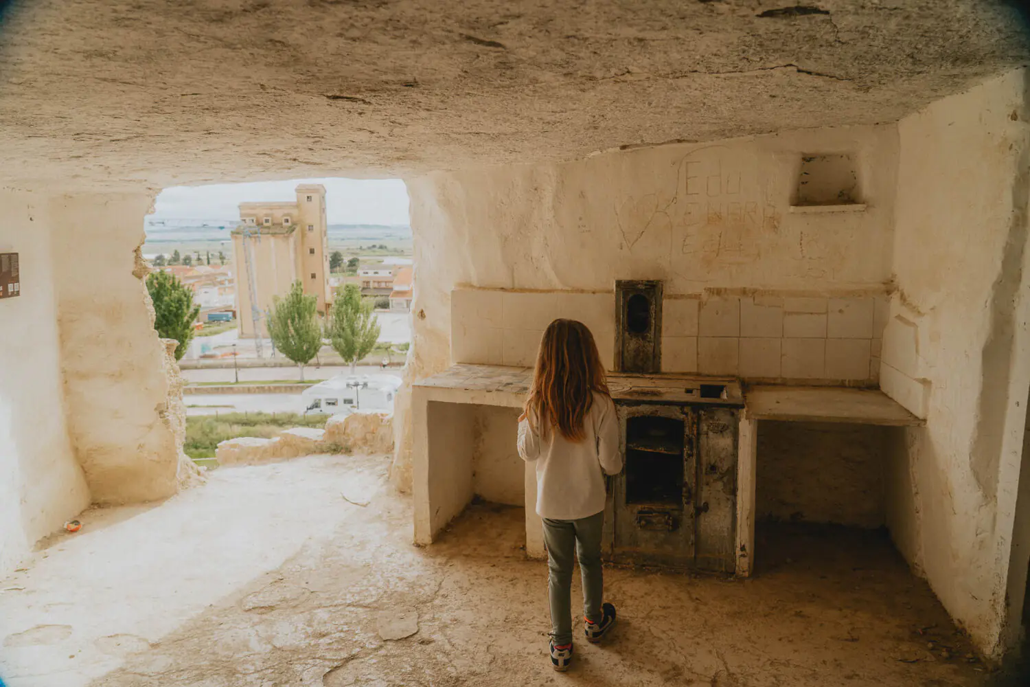 Une jeune fille contemple le paysage depuis une maison troglodytique authentique, instant de douceur capturée en famille.