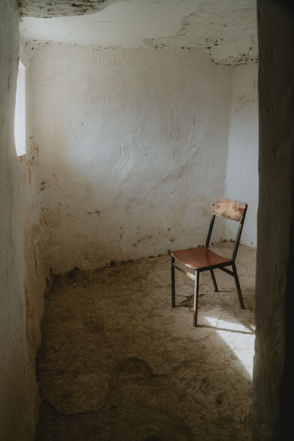Un fauteuil en bois, baigné de lumière, évoque la douceur et la simplicité dans cette maison troglodytique.