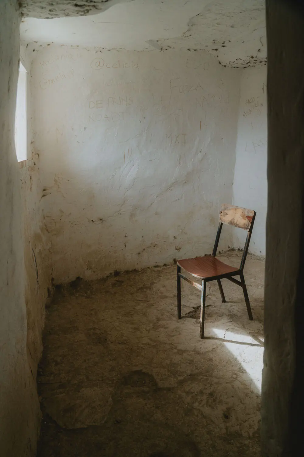 Un fauteuil en bois, baigné de lumière, évoque la douceur et la simplicité dans cette maison troglodytique.