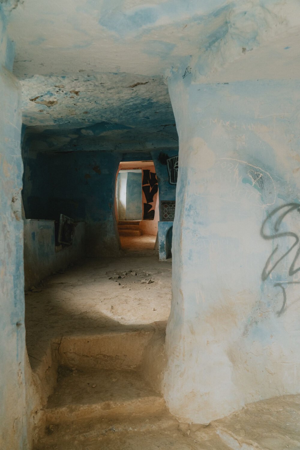 Découvrez ce couloir authentique aux murs bleus et pierres brutes, baigné de lumière douce, en maison troglodytique.