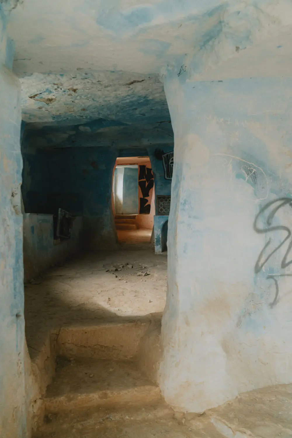 Découvrez ce couloir authentique aux murs bleus et pierres brutes, baigné de lumière douce, en maison troglodytique.