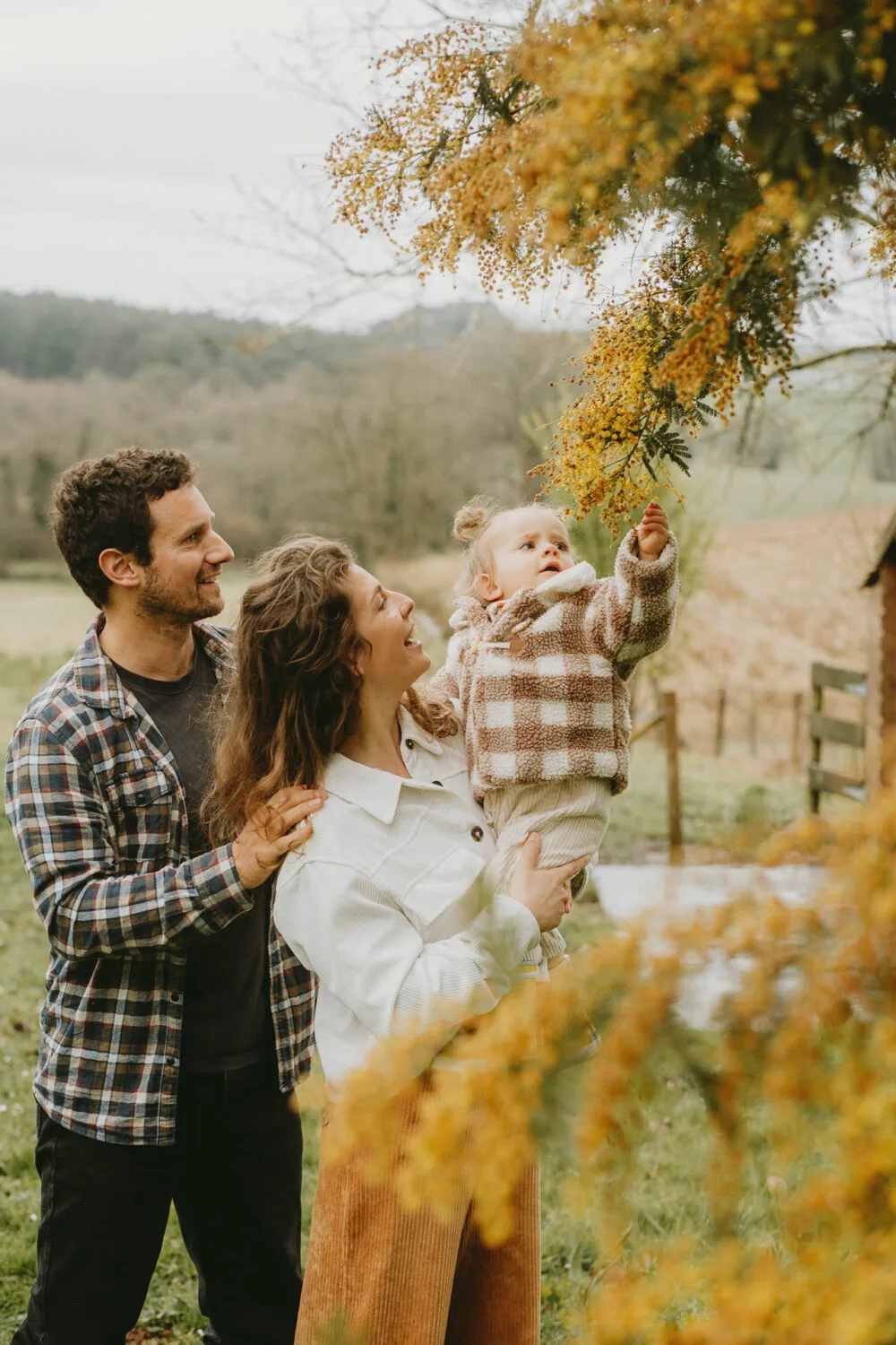 Douce scène familiale près de Dax , parents unis et enfant curieux sous les fleurs, souvenirs chaleureux de mariage.