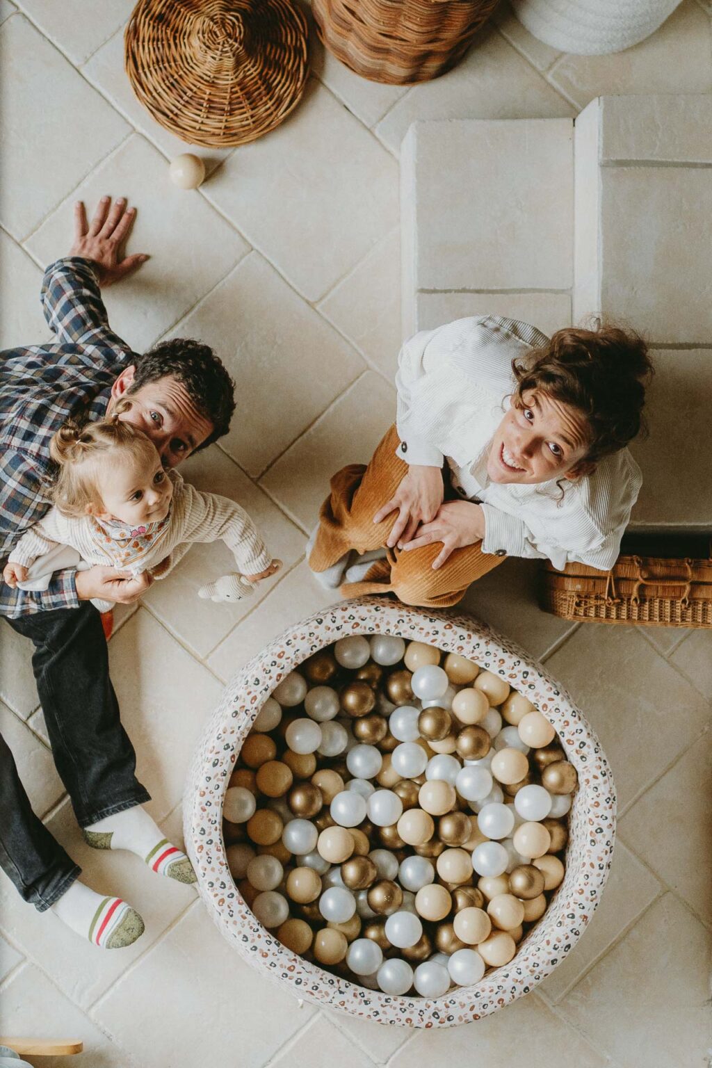 Une famille rayonnante, réunie au sol près d’un espace de jeu coloré