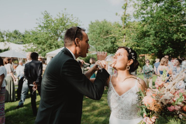 Un couple trinque tendrement au Domaine de Petiosse, entouré d'invités et de verdure lors d'un mariage champêtre dans les Landes.