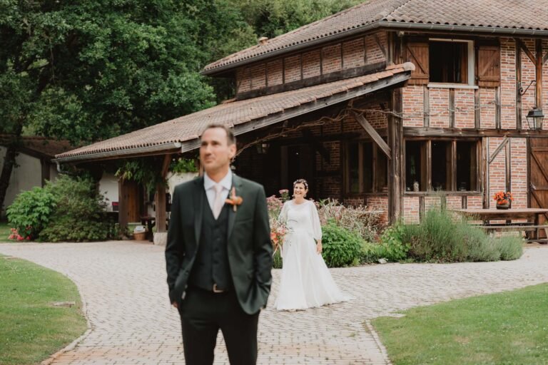 Un doux instant capturé aux Landes : la mariée rejoint son époux devant une bâtisse boisée au domaine de Petiosse.