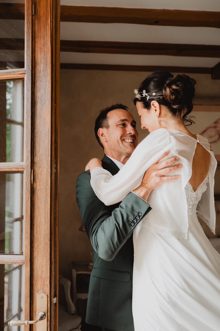 Moment tendre entre Céline et Nicolas, portés par la joie près d'une porte en bois au domaine de Petiosse, ambiance Landes.