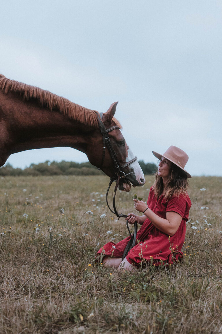 Douce scène champêtre à Mariage Dax Meysonnave : une femme en robe rouge nourrit un cheval, ambiance intime et authentique.