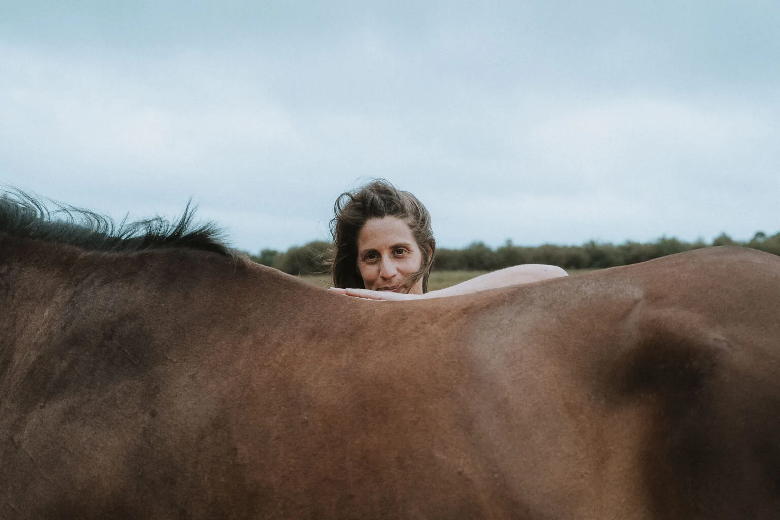 Instant douceur : une mariée enlace un cheval dans la campagne landaise, sous un ciel paisible, lors d'une célébration intime.