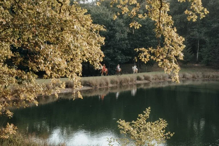 Jolie scène de mariage dans les Landes : balade à cheval près d'un étang, reflets d'arbres et ambiance paisible en famille.
