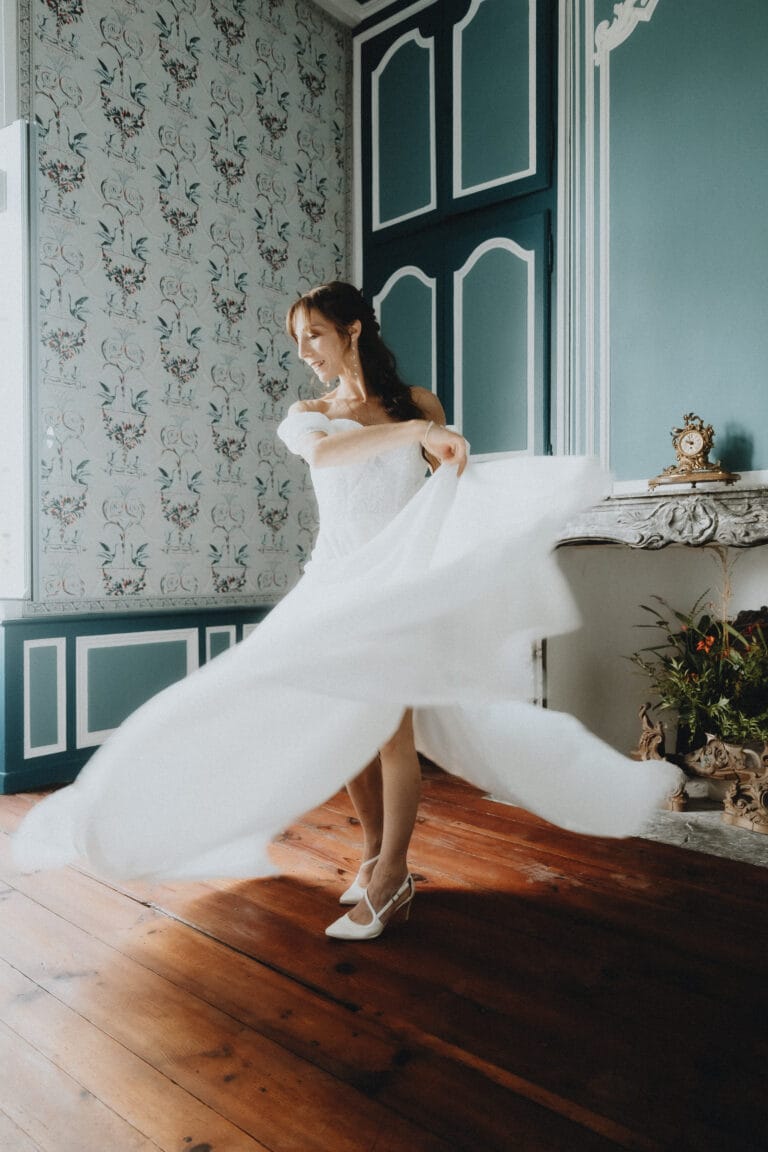 Une mariée virevolte sur un parquet ancien, baignée de lumière douce dans une salle élégante aux airs romantiques landais.