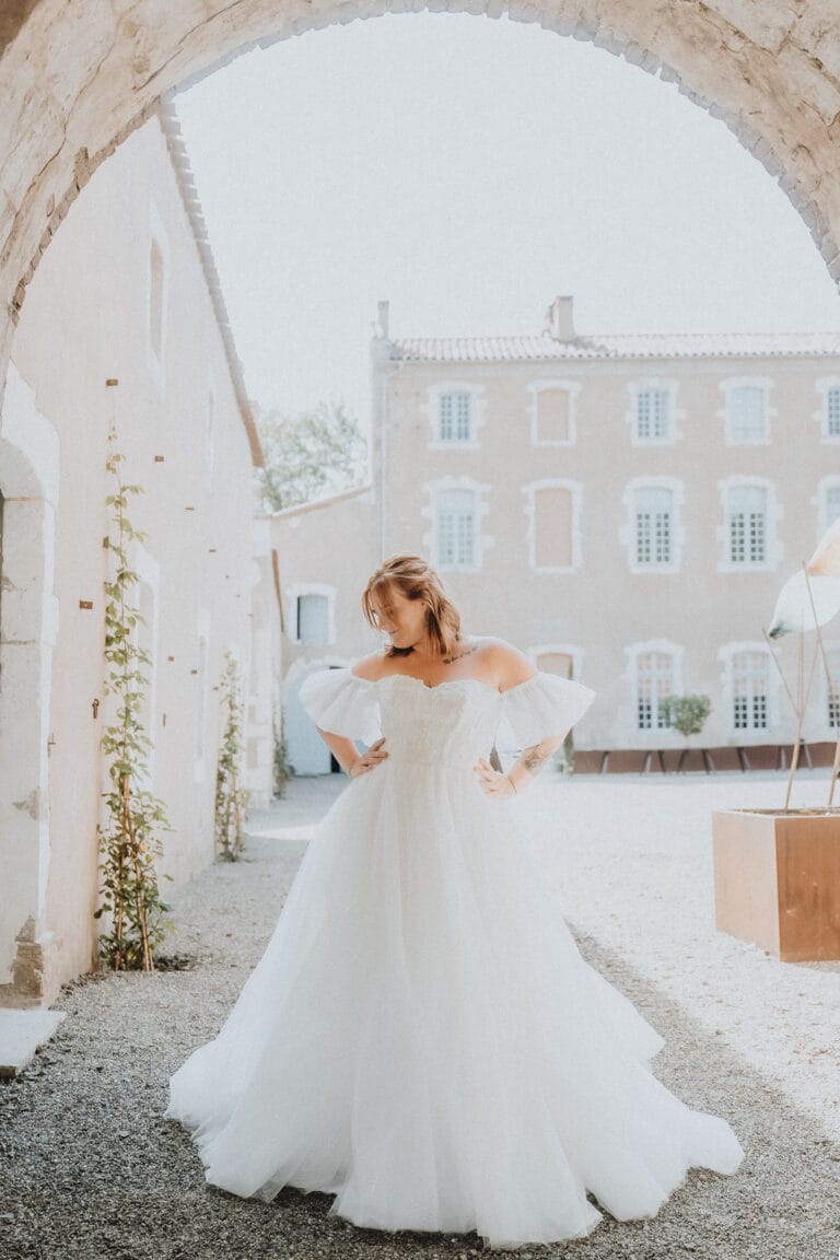 Sous la douce lumière des Landes, une mariée rayonne sous une arche, élégante devant les pierres claires de Dax Meysonnave.