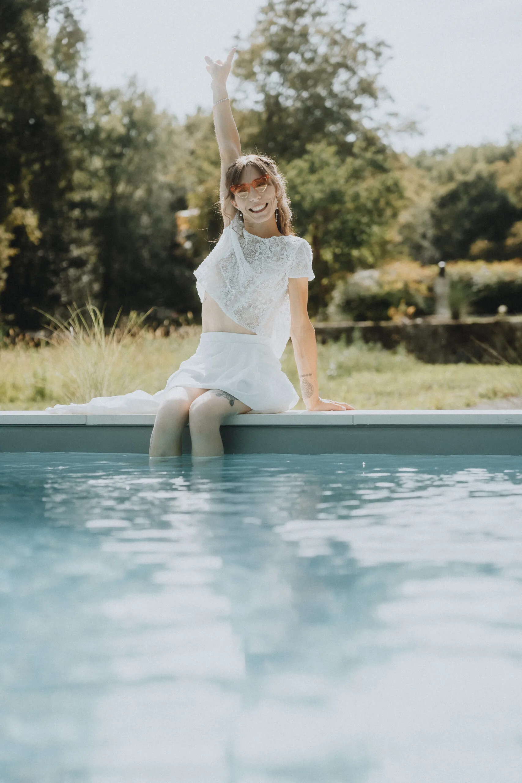 Instant tendre d'un mariage dans les Landes : sourire au bord de la piscine, robe blanche, nature verdoyante en arrière-plan.