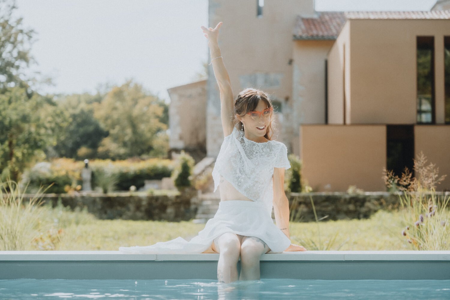 Instant précieux lors d'un mariage aux Landes : une femme élégante profite au bord de la piscine, entourée de verdure.
