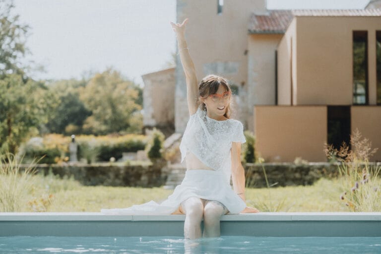 Instant précieux lors d'un mariage aux Landes : une femme élégante profite au bord de la piscine, entourée de verdure.