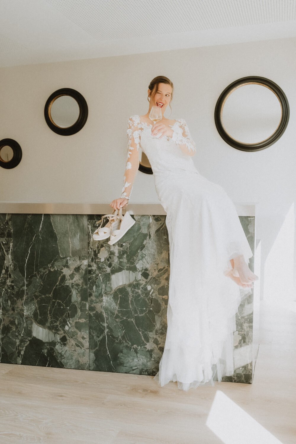 Dans l'intimité de Mariage Dax, une mariée rayonne, pieds nus sur le comptoir vert, un instant authentique et joyeux.