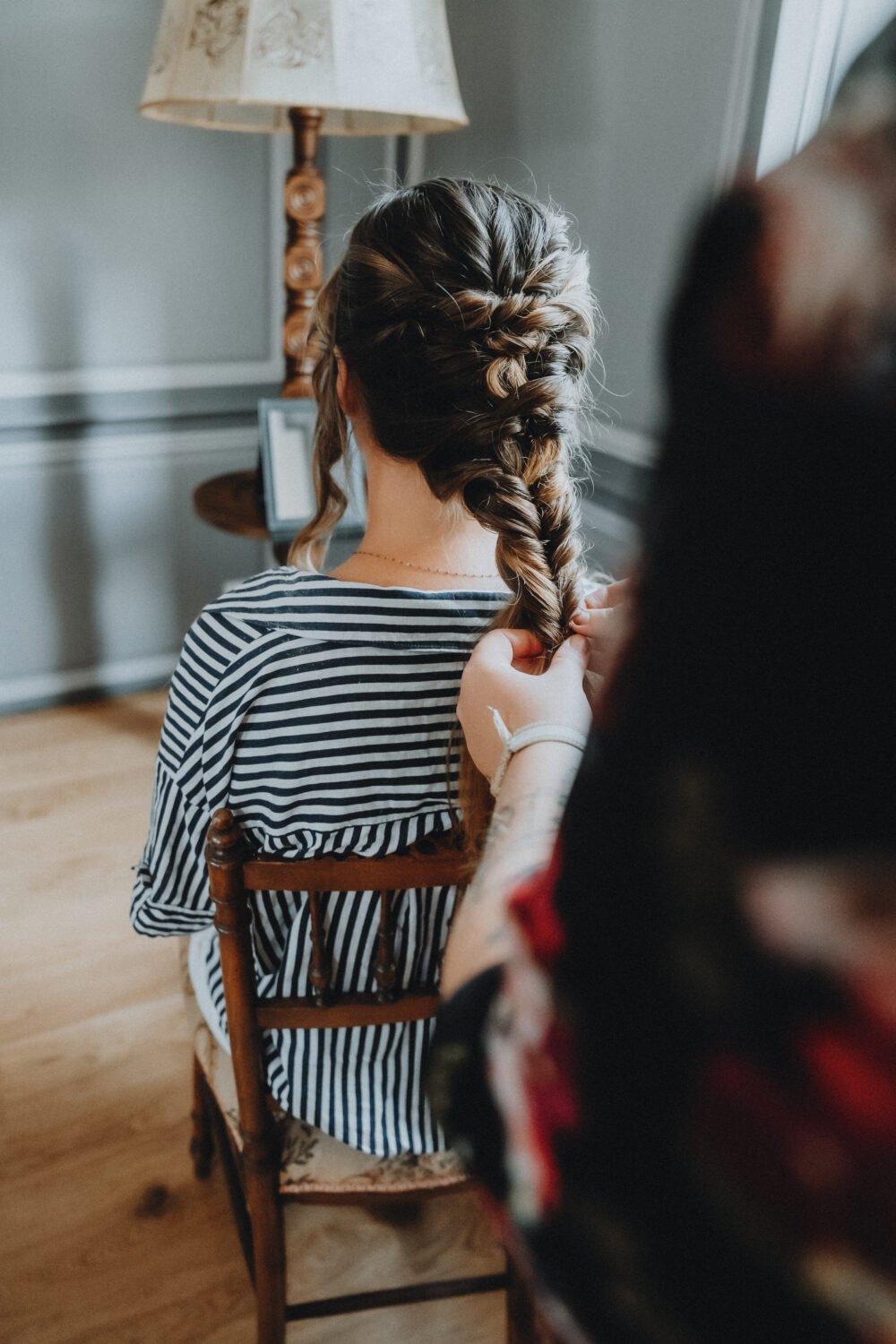 Préparation de mariage dans les Landes, moment de complicité et douceur, cheveux tressés, ambiance chaleureuse et boisée.