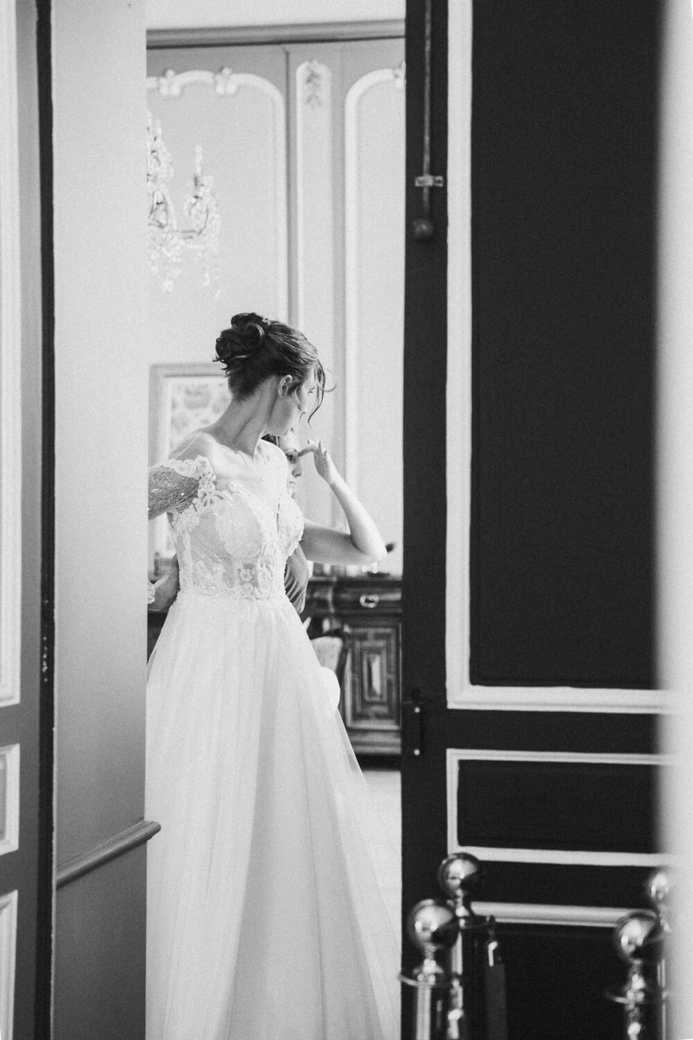 Vous êtes rayonnante dans votre robe en dentelle, près de la porte entrouverte, capturée à Dax pour ce moment précieux.