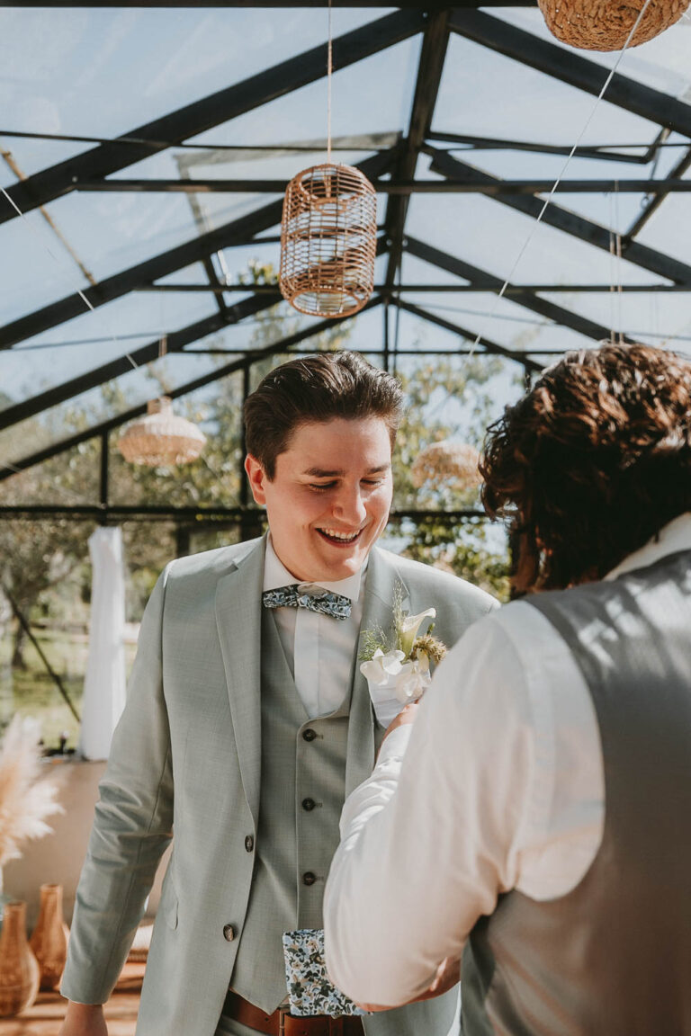 Dans une verrière baignée de lumière, un sourire complice lors d'une tendre pose boutonnière, ambiance mariage Landes.