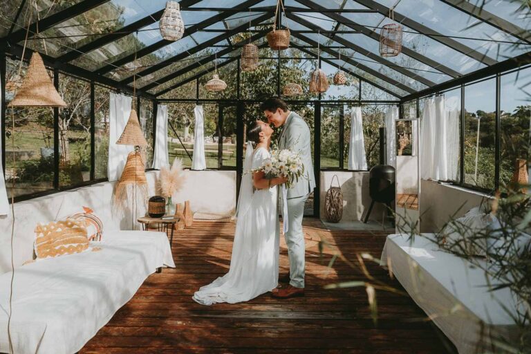 Un couple rayonnant s'enlace tendrement dans une serre baignée de lumière, décor féerique idéal photo famille Landes.