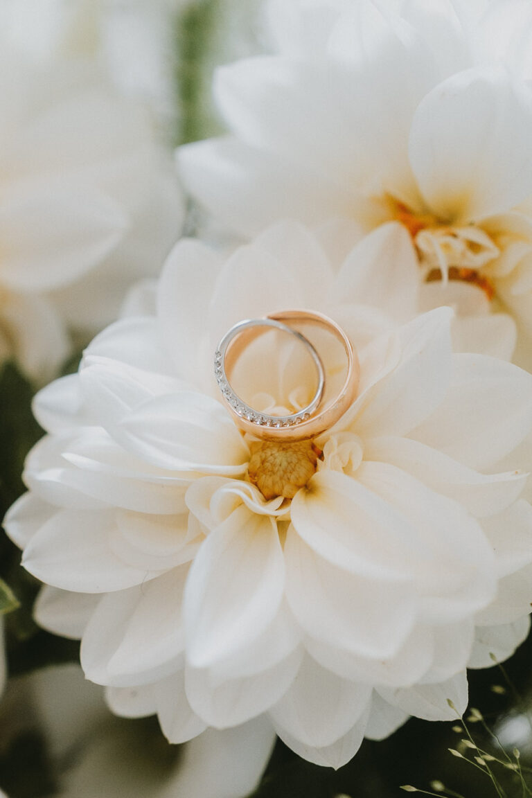 Un doux duo d'alliances posé sur une dahlia blanche, capturant l'émotion et la tendresse dans l'ambiance des Landes.