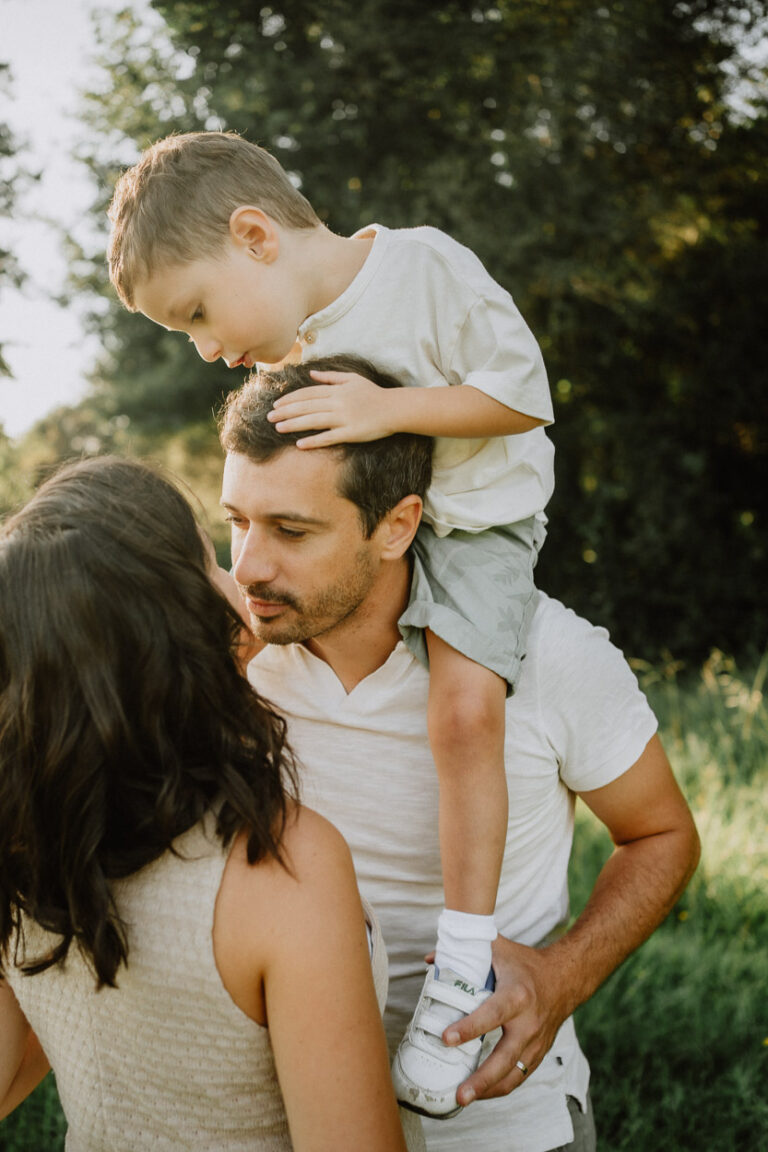 Instant tendre en famille dans les Landes, papa porte son fils près de maman. Lumière douce et nature, capturées à Dax.
