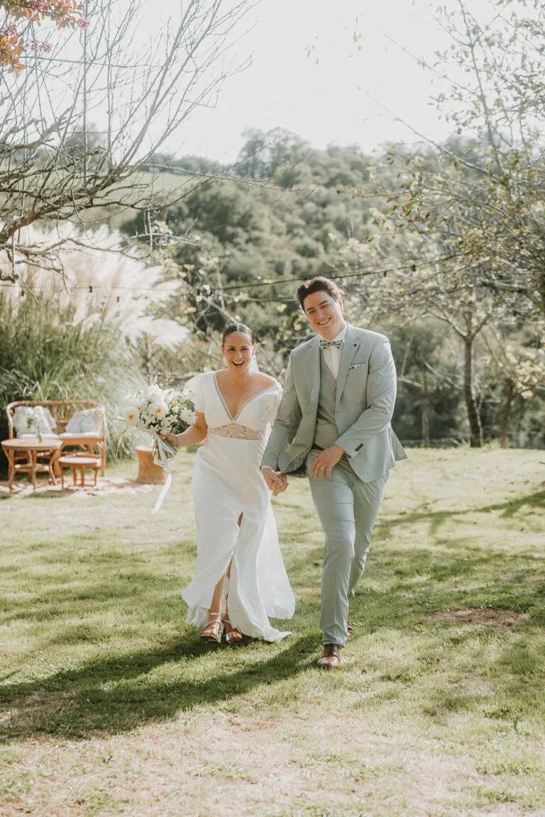 Un couple radieux main dans la main sur une pelouse, photographié près de Dax, ambiance mariage authentique dans les Landes.