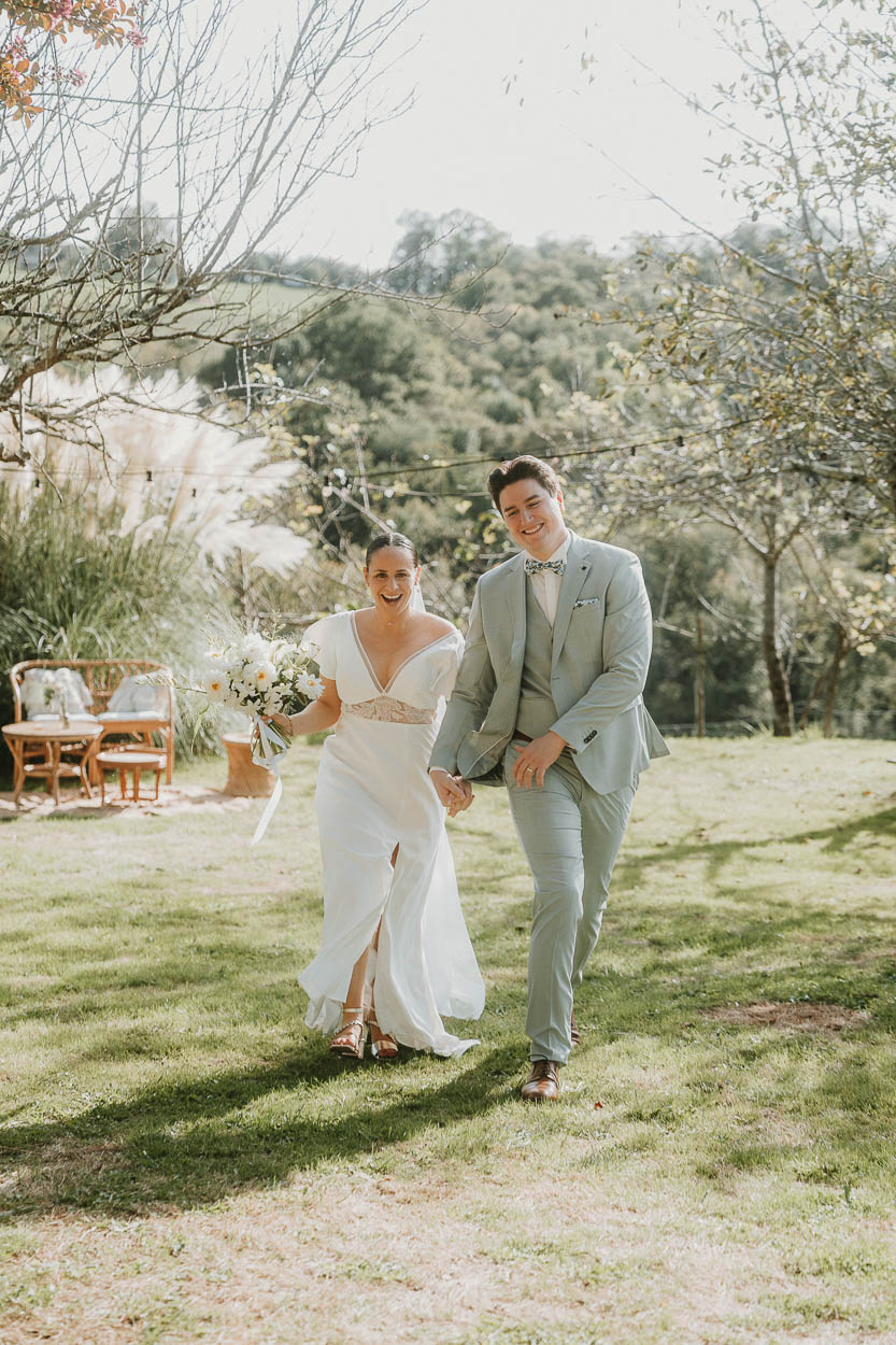 Un couple radieux main dans la main sur une pelouse, photographié près de Dax, ambiance mariage authentique dans les Landes.