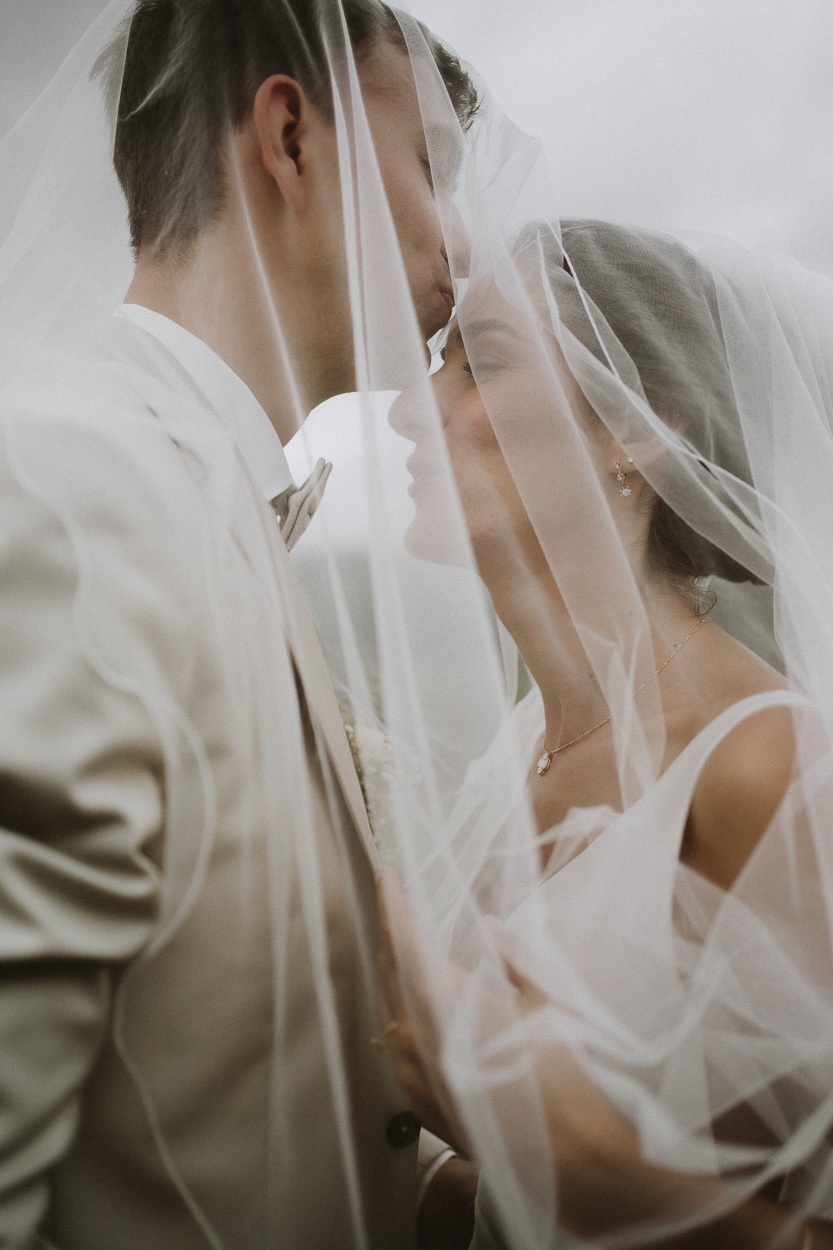 Dans le doux décor de Dax, un couple s'enlace sous un voile, capturant la tendresse d'un instant unique en Landes.