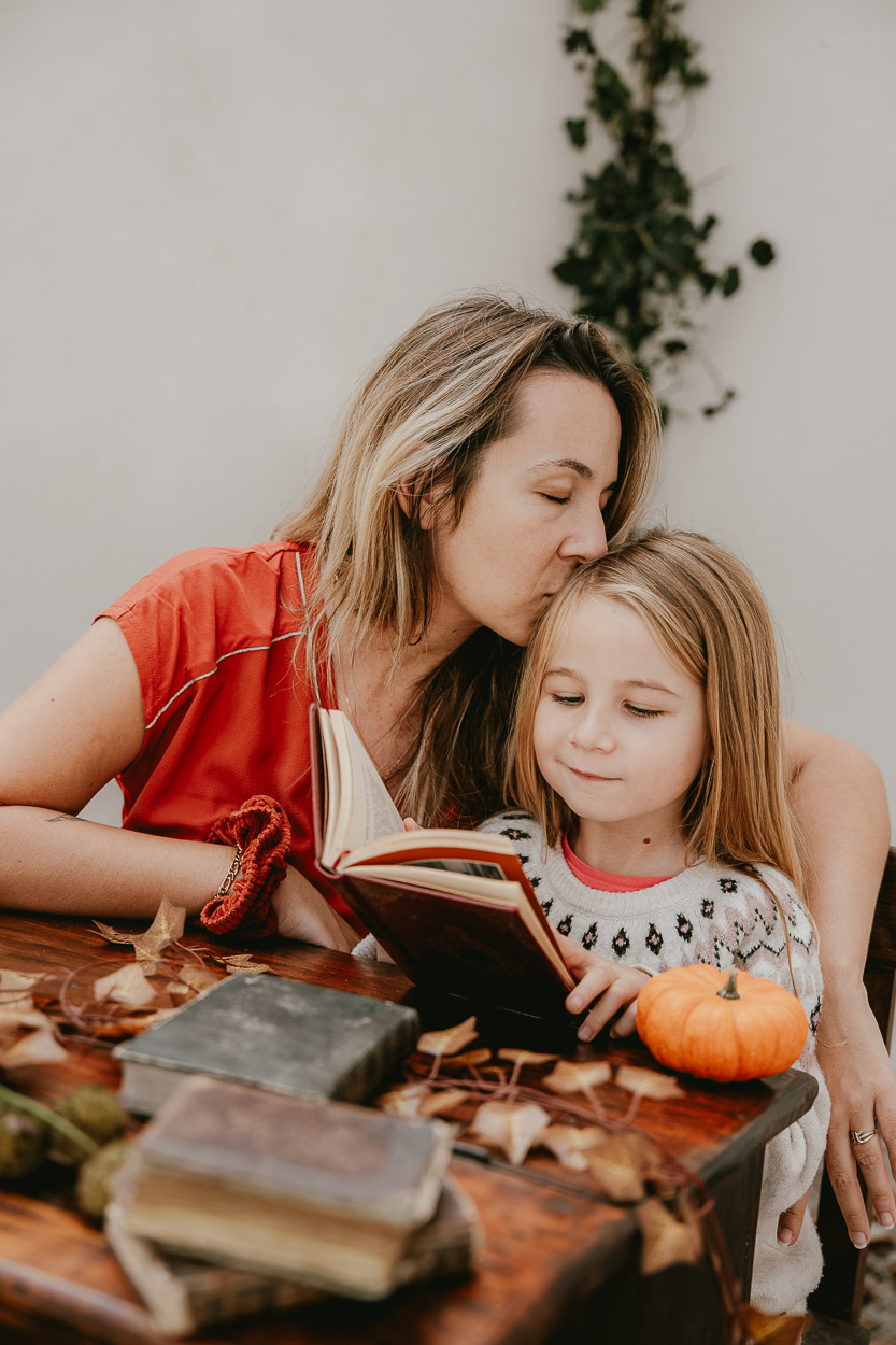 Moment tendre entre parent et enfant à Dax, lecture à table en bois, décor Landes authentique et doux, ambiance familiale.