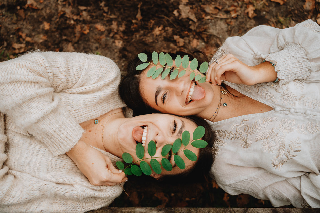 Moment complice dans la nature landaise, deux proches rient ensemble sous les feuilles, complicité et naturel en plein air.