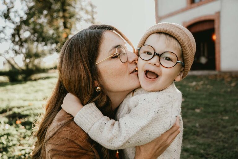 Tendresse partagée : un câlin complice parent-enfant devant un bâtiment, capturé à Dax par une photographe des Landes.