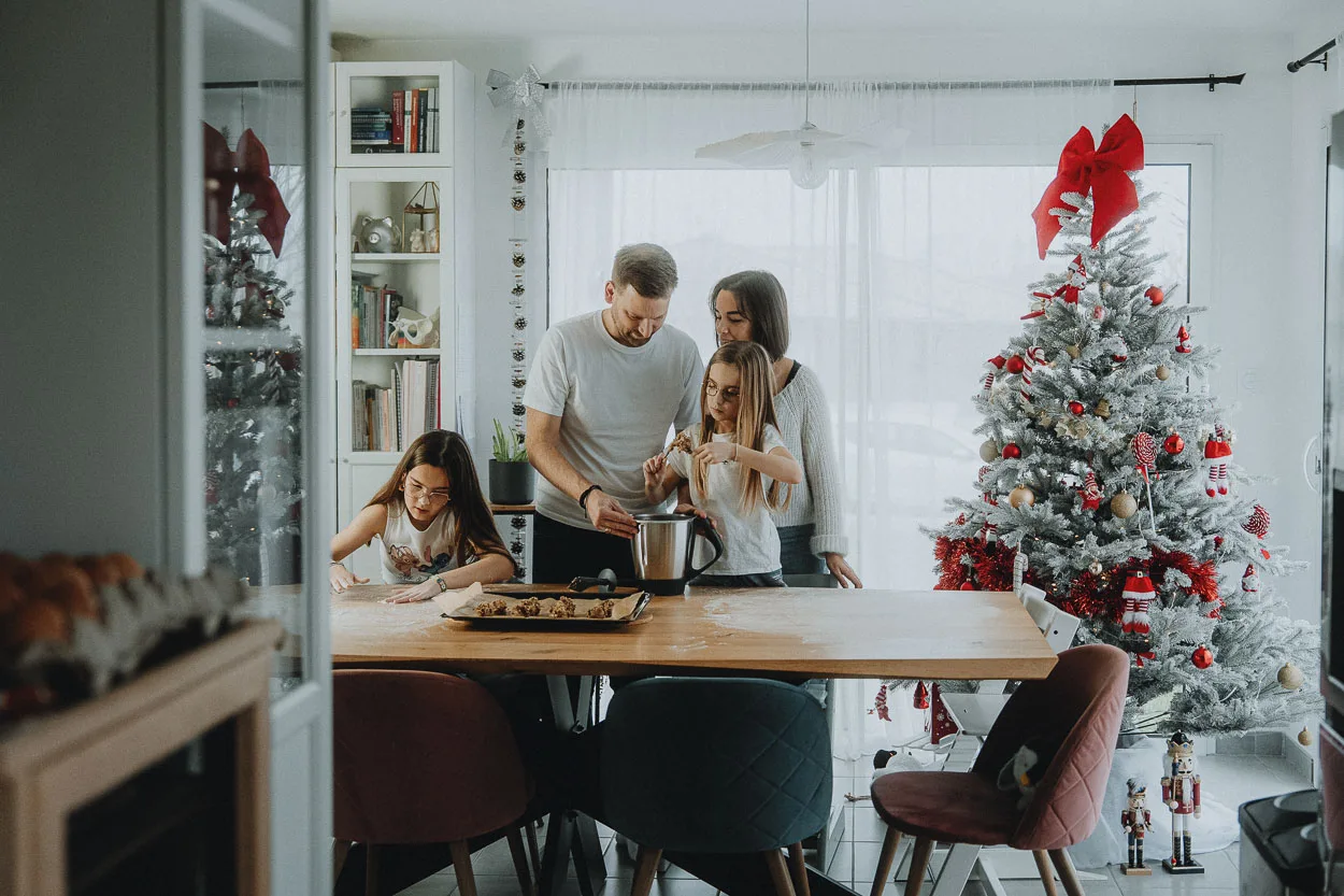 Une famille de quatre partage un doux moment en cuisine décorée, préparant des biscuits près du sapin, ambiance chaleureuse Landes.